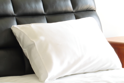 white silk pillowcase on bed with black headboard